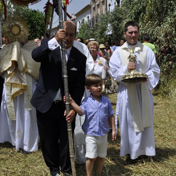 Fotografía donde observamos a un pequeño , junto a un adulto abriendo la procesión del Corpus.