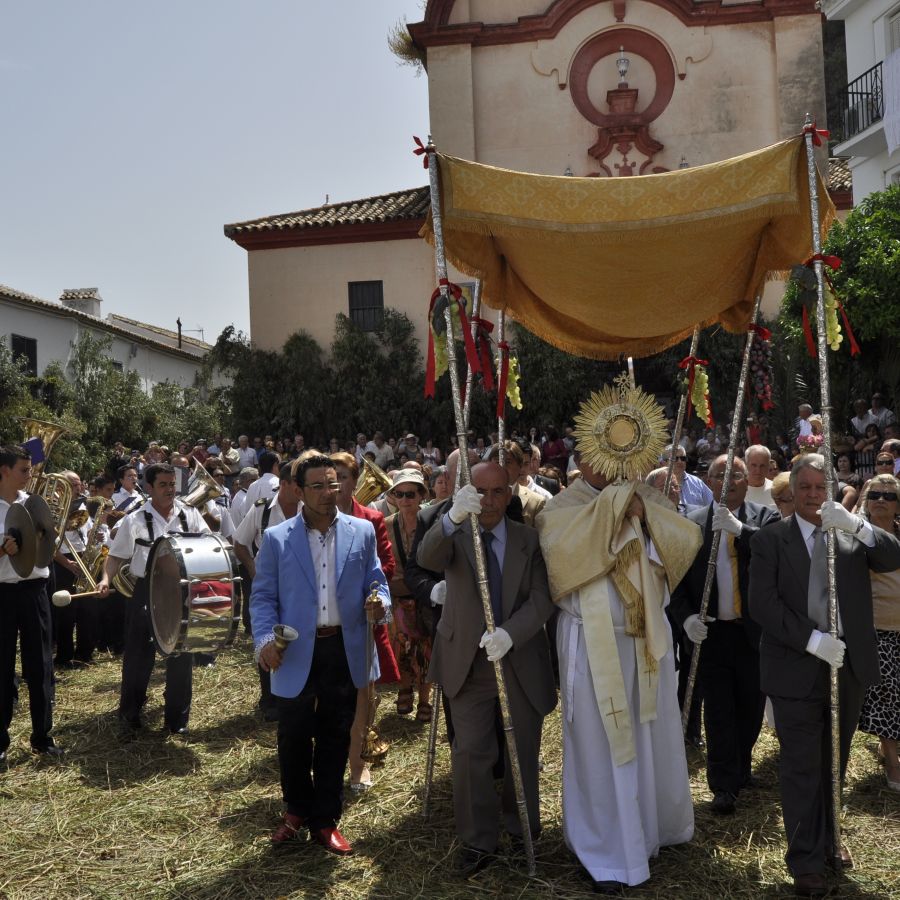 imagen donde vemos como la banda acompaña al Santísimo, mientras este procesiona por las calles de la villa.