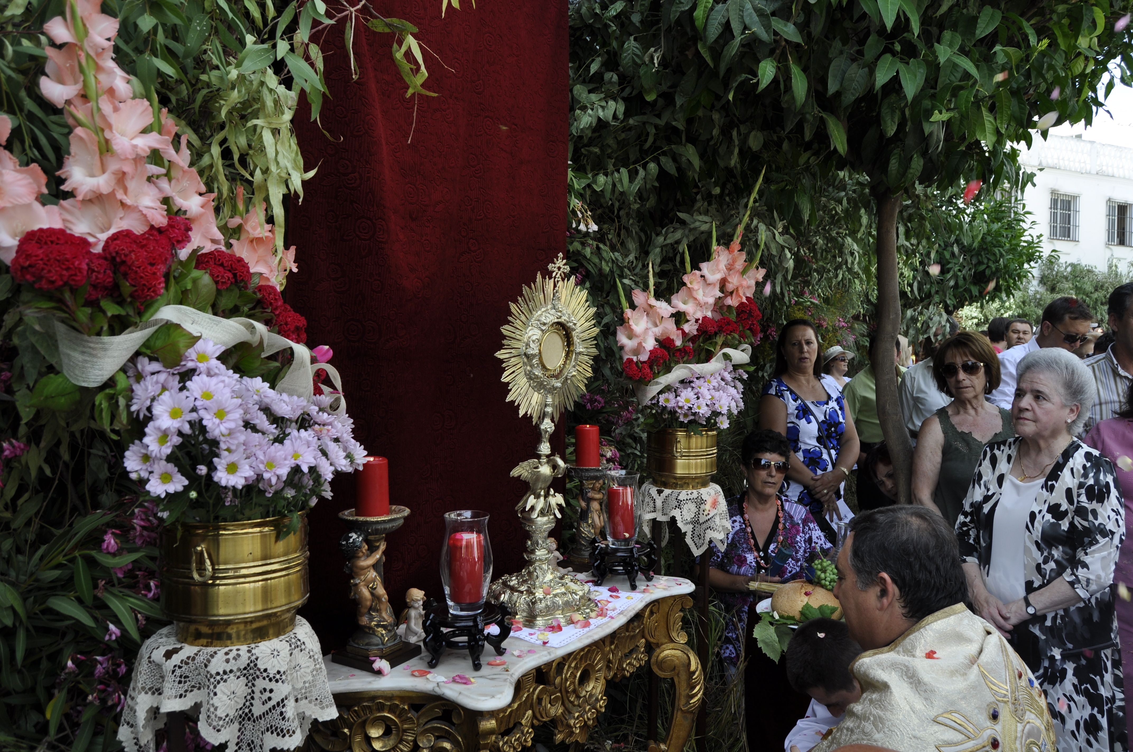 Fotografía donde vemos al párroco orando en un altar de los que están situados por las calles de la villa.