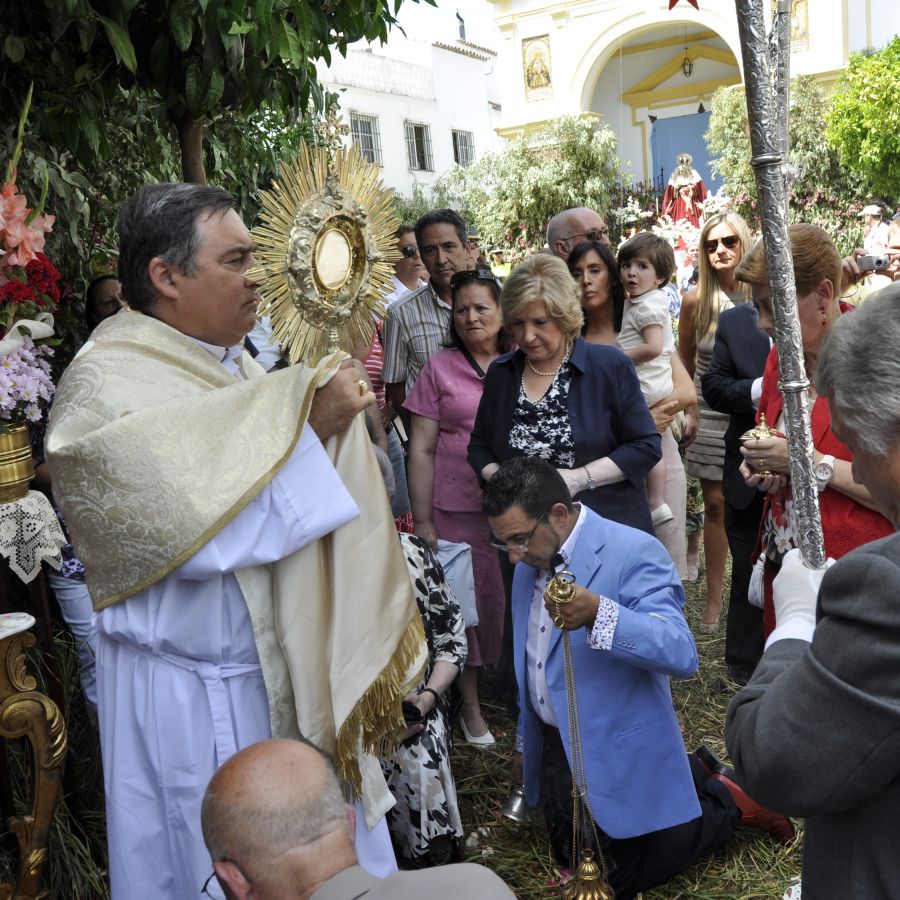 Imagen de párroco, con el Santísimo en las manos, orando junto a los ciudadanos.