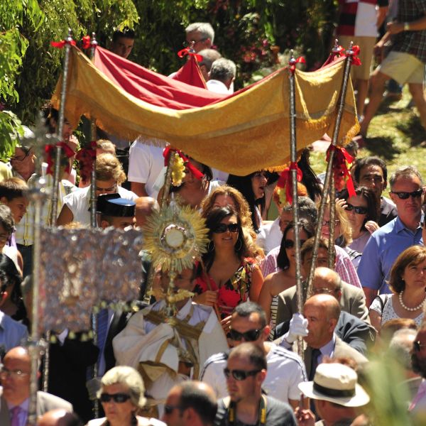 Imagen donde se ve procesionar al Santísimo rodeado de gente.