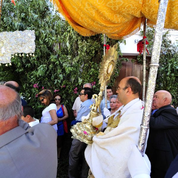 Imagen donde se ve procesionar al Santísimo rodeado de gente.